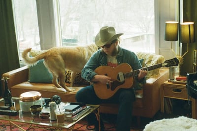 An artist playing guitar in a living room during a filmed session