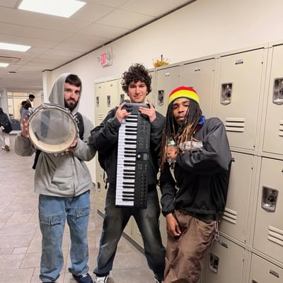 Three students at school lockers carrying a snare drum and a keyboard