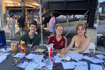 Young people filling in Songs That Found Me cards at a festival table