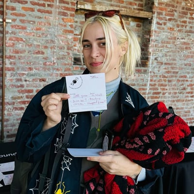 Someone holding up a filled-in Songs That Found Me card against a brick wall