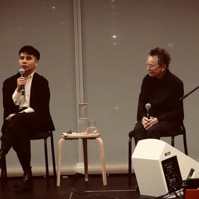 Two people in conversation on stools with microphones