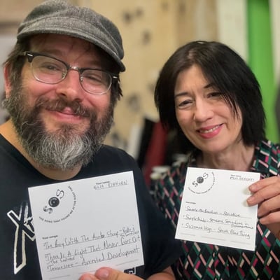 Two people holding up completed Songs That Found Me cards